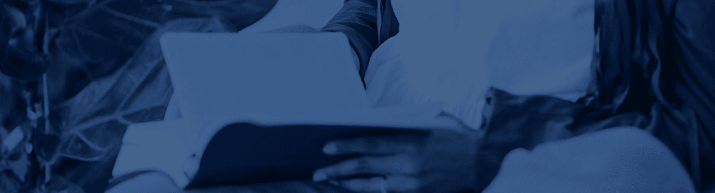 A wide banner with a monochrome blue overlay showing a close-up of someone reading a book.