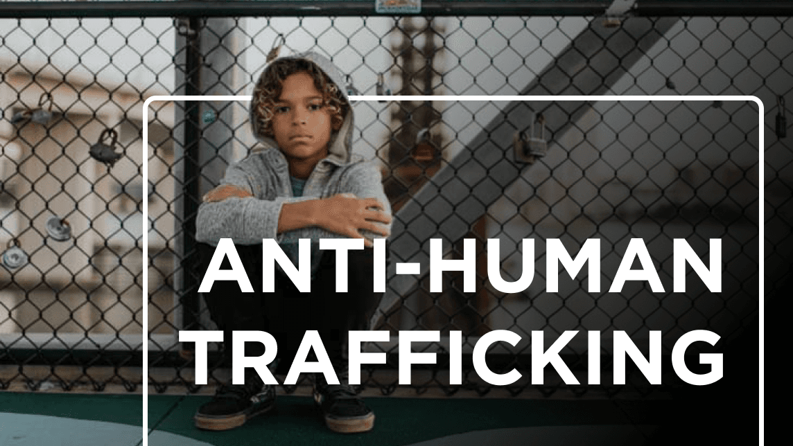 Child sitting alone behind a chain-link fence with the overlaid text “ANTI-HUMAN TRAFFICKING.”