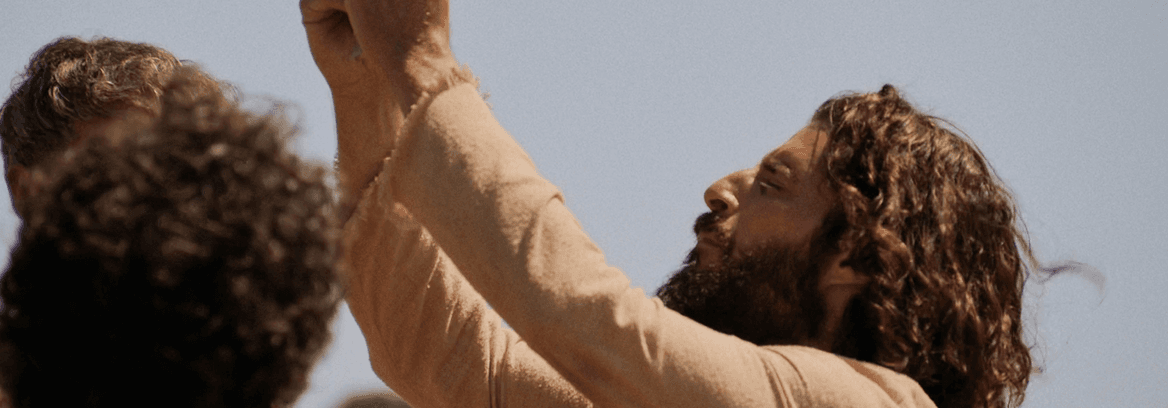 Jesus looks upward raised arms in daylight.