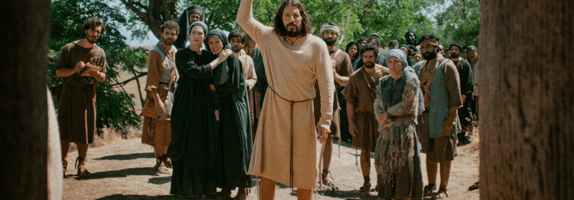Jesus stands with arm raised before a group of concerned onlookers.